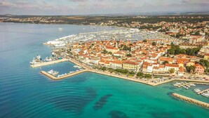 Vue aérienne d’une ville côtière avec un port de plaisance, des immeubles résidentiels et une mer d’un bleu limpide.