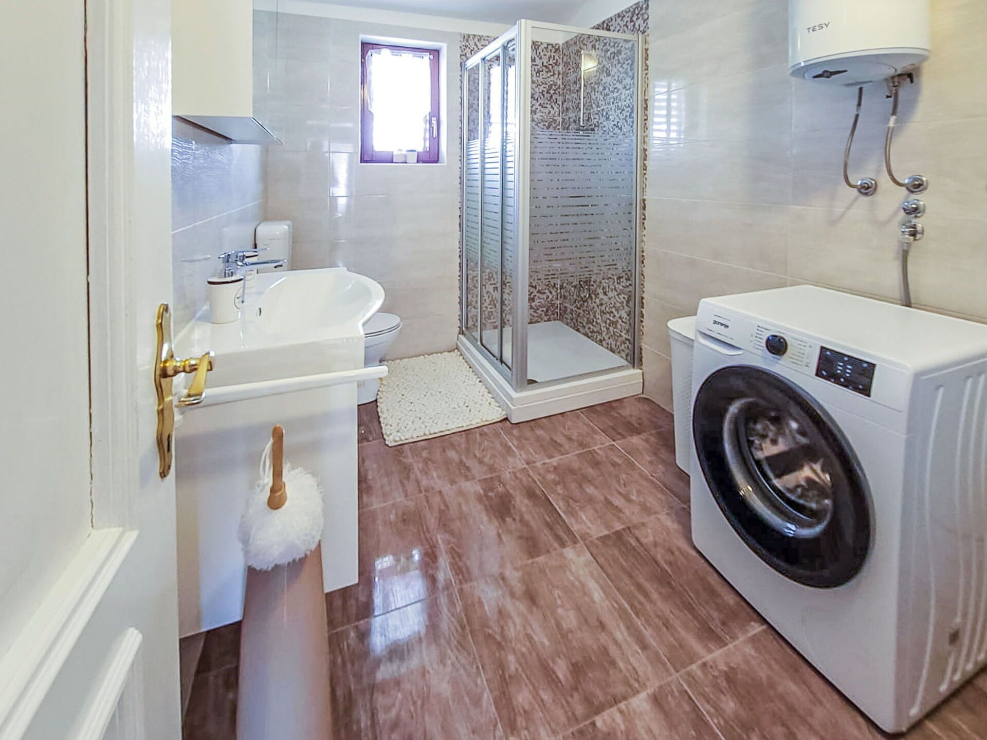 Un baño moderno con lavabo, inodoro, ducha y lavadora.