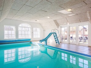 An indoor swimming pool with a slide, large windows, and a view of the outside. - 4 Star Holiday Home in Ulfborg (Ulfborg)