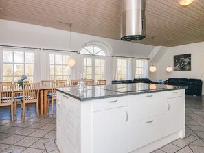 A spacious kitchen with a large island, wooden chairs, and a dining table.