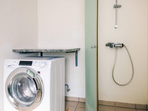 Une machine à laver et une douche dans une pièce dont le sol est carrelé.