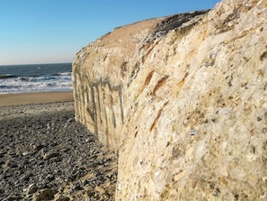 Une falaise côtière avec une plage rocheuse au premier plan et l’océan en arrière-plan.