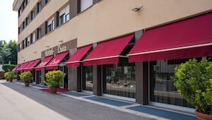 A hotel with multiple red awnings and large windows. - Hotel Bulà (Bollate)