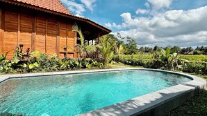 A wooden building with a pool surrounded by tropical plants. - Jagadhita Villas Ubud Bali (Ubud)