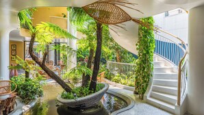 An indoor atrium with a central water feature, surrounded by lush greenery and a spiral staircase. - Saha Casa Boutique Hotel Da Nang (Da Nang)