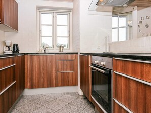 Une cuisine avec des armoires en bois, une fenêtre et un four encastré.