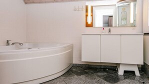 A bathroom with a freestanding bathtub, a white vanity with a mirror, and a tiled floor. - 4 Star Holiday Home in Ulfborg (Ulfborg)
