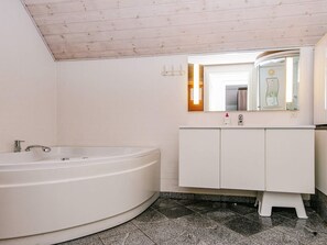 A bathroom with a freestanding bathtub, a white vanity with a mirror, and a tiled floor. - 4 Star Holiday Home in Ulfborg (Ulfborg)
