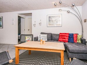Un salon moderne avec un canapé gris, une table basse en bois et un tapis aux motifs noir et blanc.