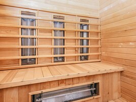 Una sauna con paredes y bancos de madera, con ventanas de malla y un banco de madera en primer plano.
