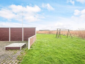 A grassy outdoor area with a wooden playset and a brick structure. - 4 Star Holiday Home in Ulfborg (Ulfborg)