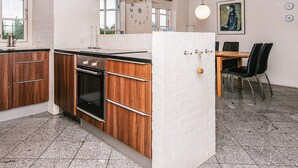 Een moderne keuken met houten kastjes, een ingebouwde oven en een witte bakstenen achterwand.