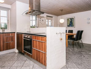 Egy modern konyha, melynek berendezésében fa szekrények, beépített sütő és fehér téglaburkolat található.