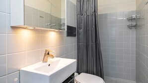 A modern bathroom with a white sink, a toilet, and a shower curtain. - 5 Person Holiday Home on a Holiday Park in Lemvig (Lemvig)