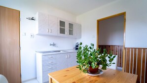 A modern kitchen with white cabinets, a wooden table, and a potted plant. - Wonderful private villa for 5 guests with WIFI, TV and terrace (Chlumec Nad Cidlinou)