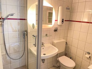 Bathroom features a glass-enclosed shower, sink, and toilet.