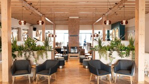 Un hall d’entrée spacieux avec des poutres en bois, des meubles modernes et des plantes en pot.