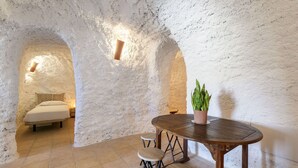 Una habitación rústica con cama, una mesa con taburetes y una planta en maceta.
