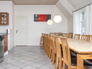 A dining area with a long wooden table and chairs, a white door, and a painting on the wall. - 4 Star Holiday Home in Ulfborg (Ulfborg)