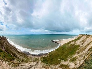 A coastal landscape with cliffs, a beach, and the ocean under a cloudy sky. - 4 Star Holiday Home in Ulfborg (Ulfborg)