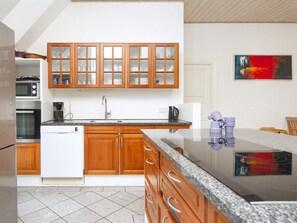 A modern kitchen with wooden cabinets, a built-in oven, and a granite countertop. - 4 Star Holiday Home in Ulfborg (Ulfborg)