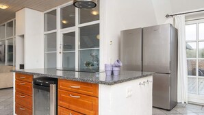 A modern kitchen with a built-in island, stainless steel appliances, and a view to the outside. - 4 Star Holiday Home in Ulfborg (Ulfborg)
