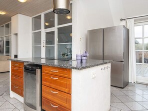 A modern kitchen with a built-in island, stainless steel appliances, and a view to the outside. - 4 Star Holiday Home in Ulfborg (Ulfborg)