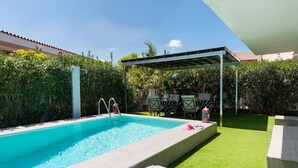 Une piscine dotée d’un espace de repos couvert, de chaises longues et d’une table avec des magazines.