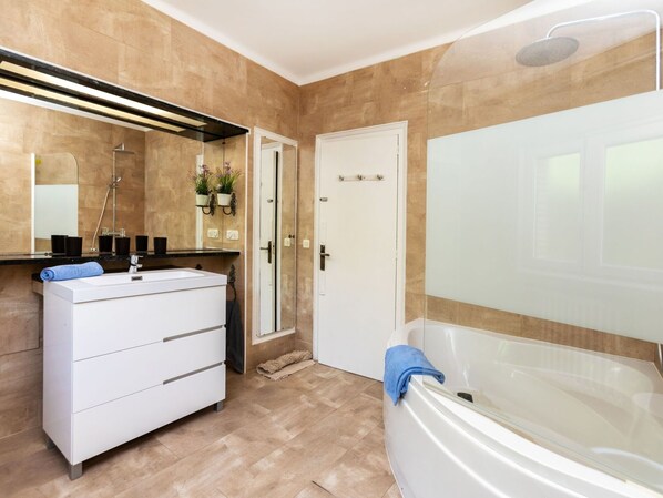 A modern bathroom with a large bathtub, a vanity with a mirror, and a shower area.