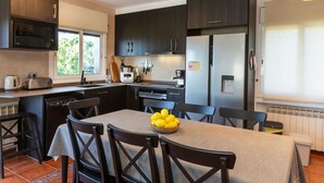 A modern kitchen with dark cabinets, stainless steel appliances, and a dining area with a table set for four.