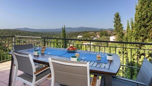 A terrace with a table set for two, chairs, and a view of the countryside.