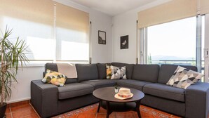 A modern living room with a gray sectional sofa, a round coffee table, and a potted plant.
