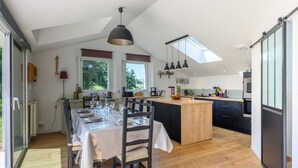 A modern kitchen with a central island, large windows, and a dining area with a table set for four.