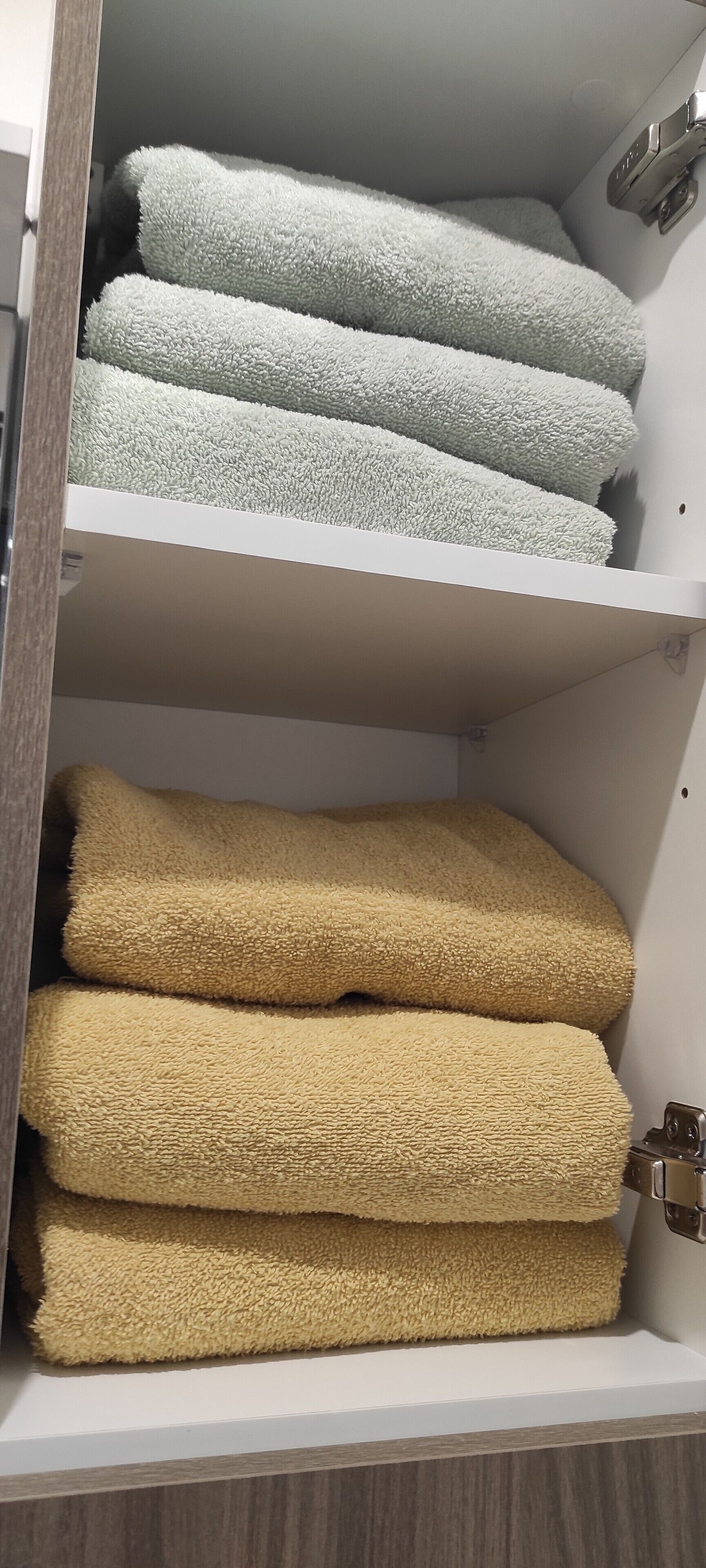 Un compartimento con toallas dobladas ordenadamente en tonos blanco y beige.