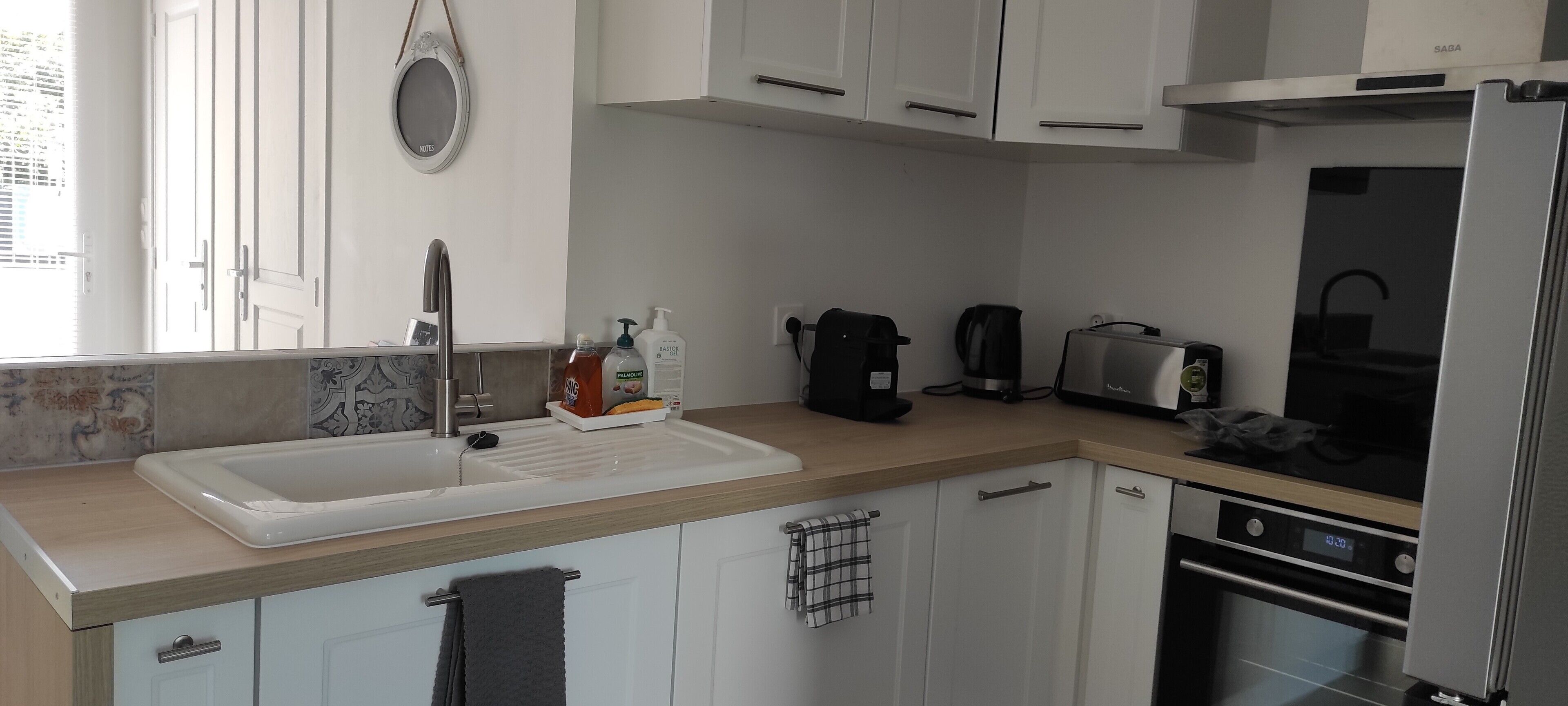 Eine Küche mit Spüle, Arbeitsplatte, Schränken, einer Kaffeemaschine, einem Toaster und einem Backofen.