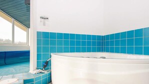 Ein Badezimmer mit einer Badewanne, blauen Fliesen und einem Fenster.