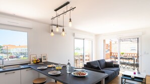 Et moderne køkken med en central ø, barstole, et spisebord og en sofa.