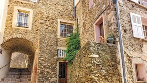 A stone building with a wooden door, a window with metal bars, and a small balcony with a plant. - Cosy apartment for 4 people with WIFI, pool, A/C, TV, balcony and pets allowed (Sainte-maxime)