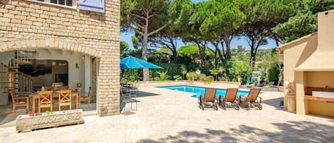 A stone building with a pool, outdoor seating, and a staircase.