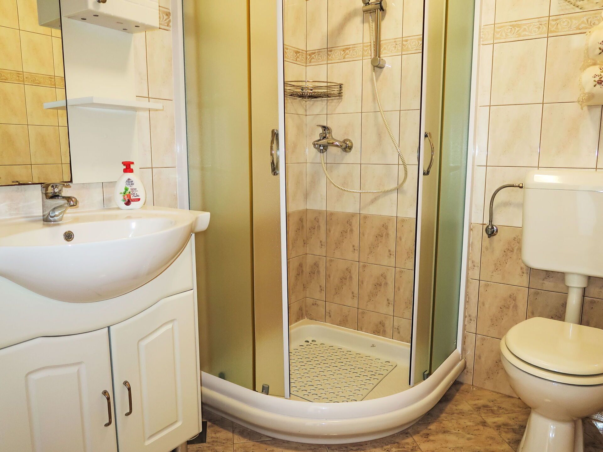 Ein Badezimmer mit einem weißen Waschbecken, einer Toilette und einer Duschkabine.