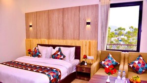 A hotel room with a large bed, a sofa, a wooden headboard, and a window with a view. - Hotel Saif Ranthambore (Sawai Madhopur)