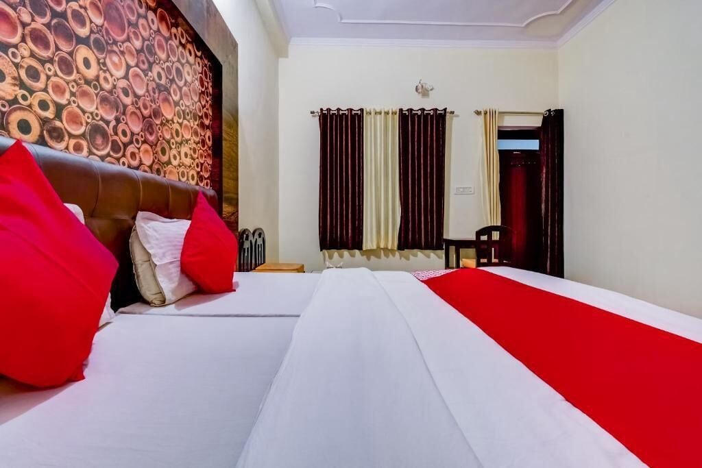 Ein Hotelzimmer mit einem großen Bett, einem Kopfteil mit kreisförmigem Muster und einer rot-weißen Bettdecke.