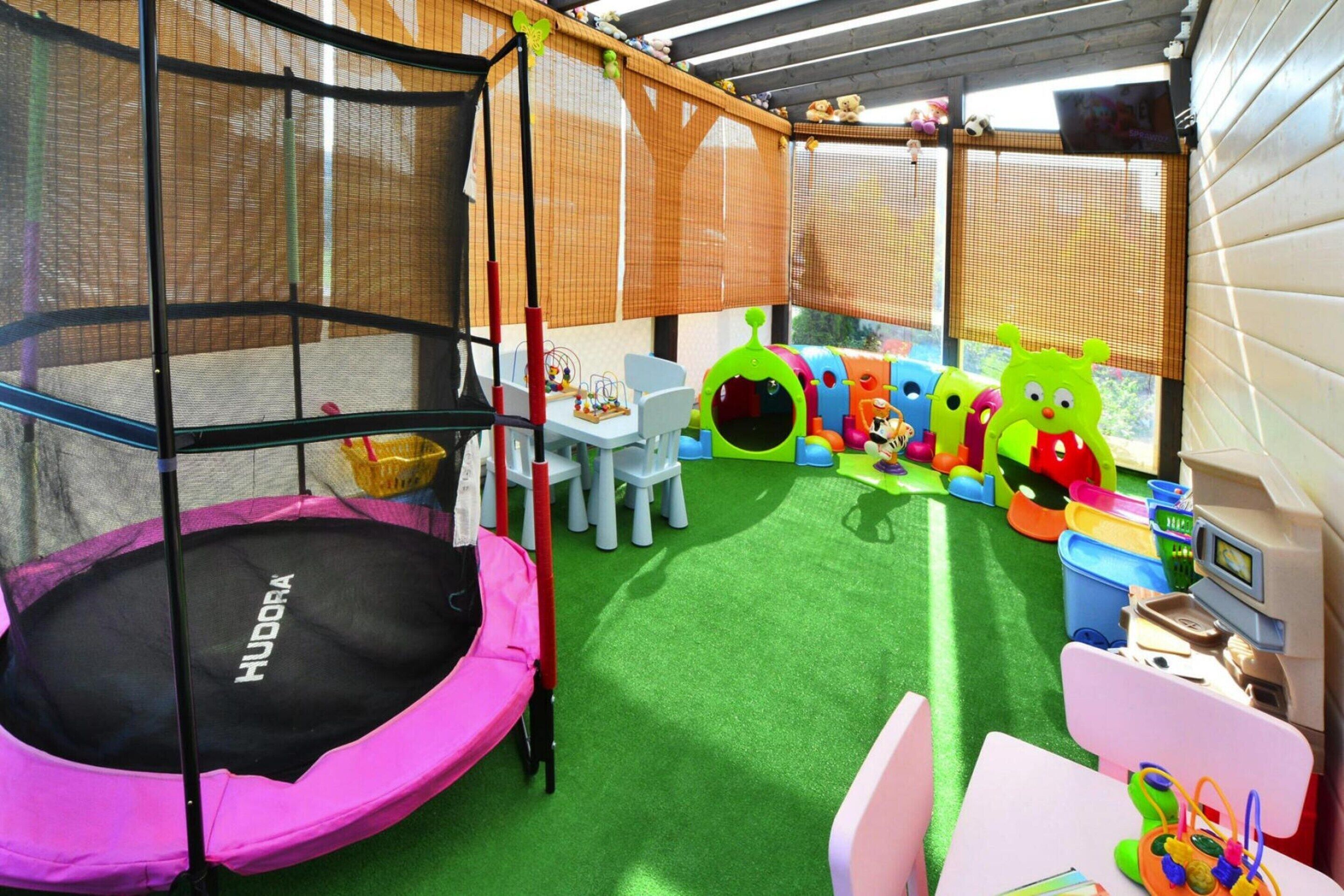 A children's play area with a trampoline, play tables, and colorful toys.