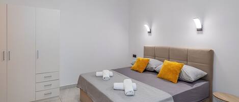 Un dormitorio moderno con cama, armario y dos luces fijadas a la pared.