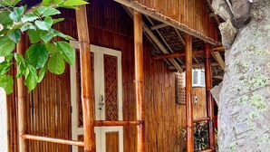 A traditional bamboo structure with a wooden porch and a thatched roof. - Treasure Beach Co.  (Carles)