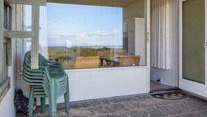 A balcony with a view of the countryside, a wicker chair, and a plastic chair. - 3 Person Holiday Home in Fano-by Traum (Fano)