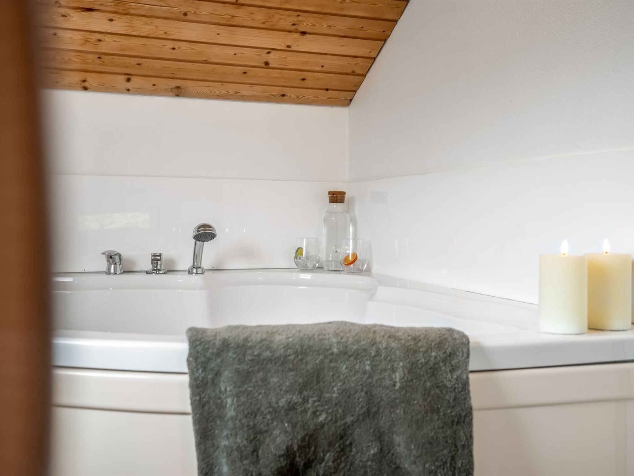 Un baño con una bañera, una toalla y dos velas.