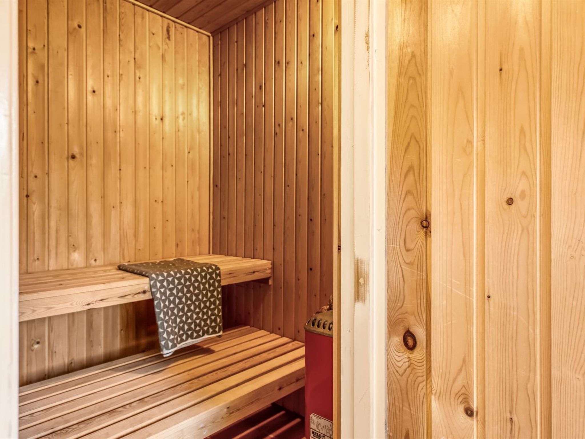 A wooden sauna with benches and a towel rack.