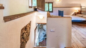 A rustic interior with a wooden staircase, a stone wall, and a bed with a patterned bedspread. - Wonderful private villa for 6 guests with WIFI, TV, patio and pets allowed (Rialto)