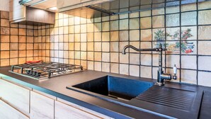 A kitchen with a gas stove, black sink, and a tiled backsplash. - Wonderful private villa for 6 guests with WIFI, TV, patio and pets allowed (Rialto)